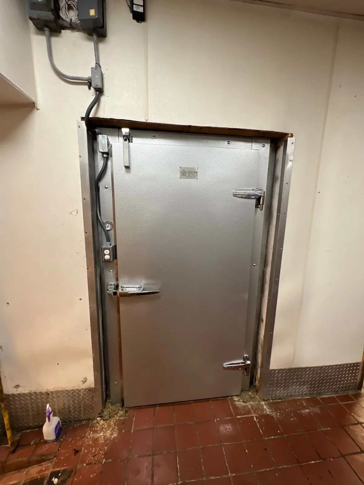 Newly installed stainless steel walk-in cooler door with a rebuilt frame and fresh gasket