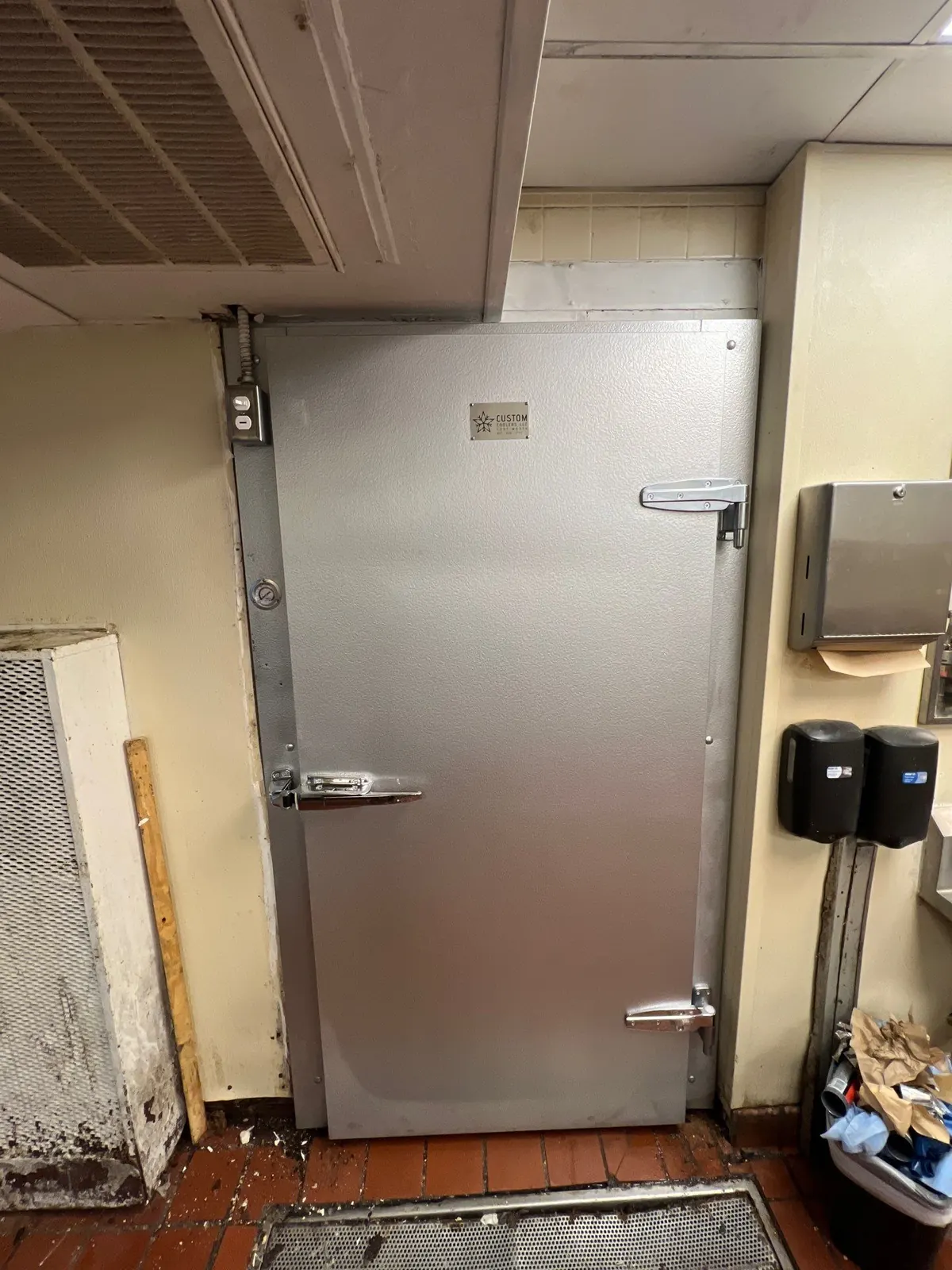 Replacement walk-in cooler door installed square in a commercial kitchen, sealing and latching again