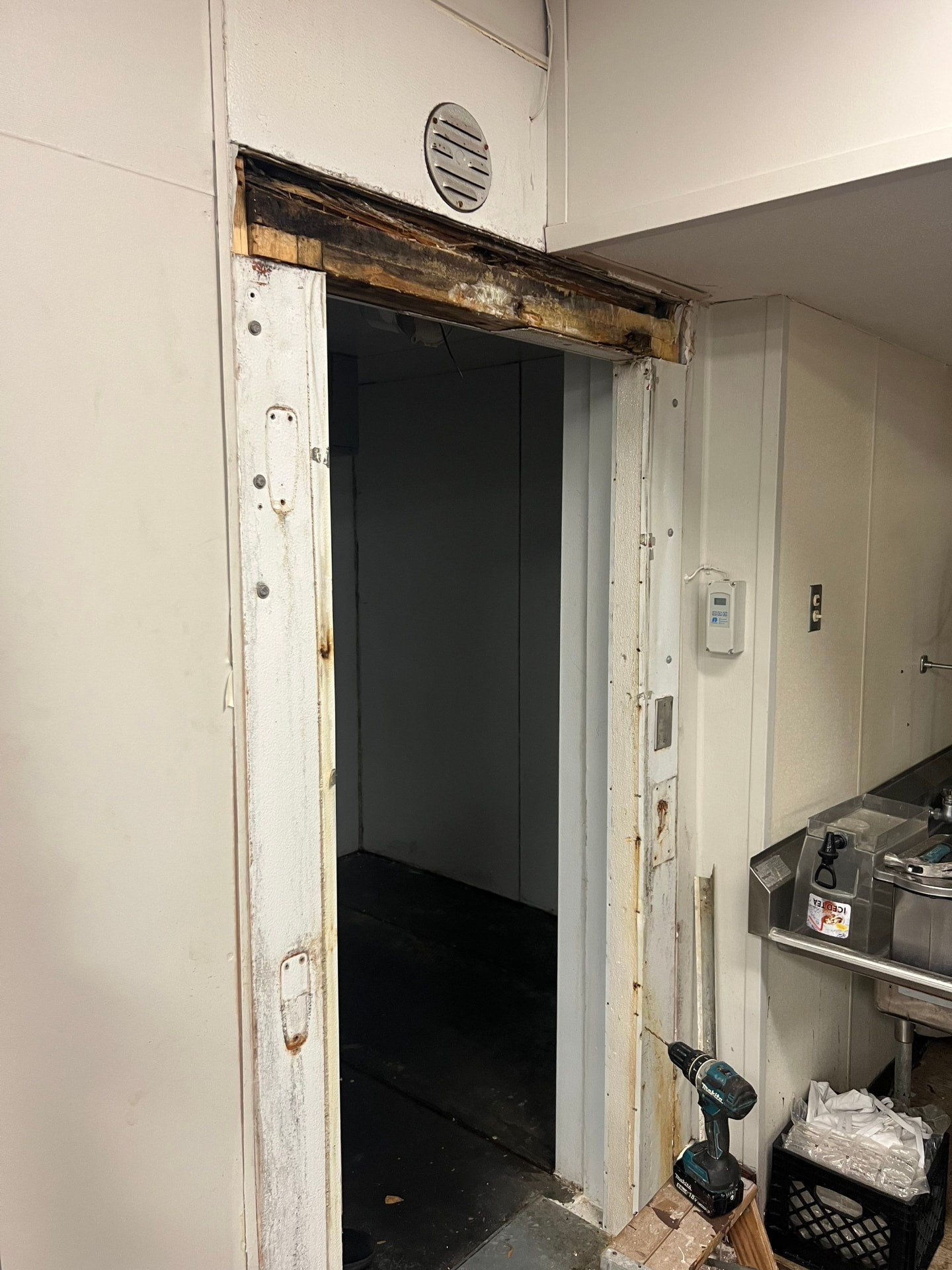 Rotted wooden header above a walk-in cooler door opening