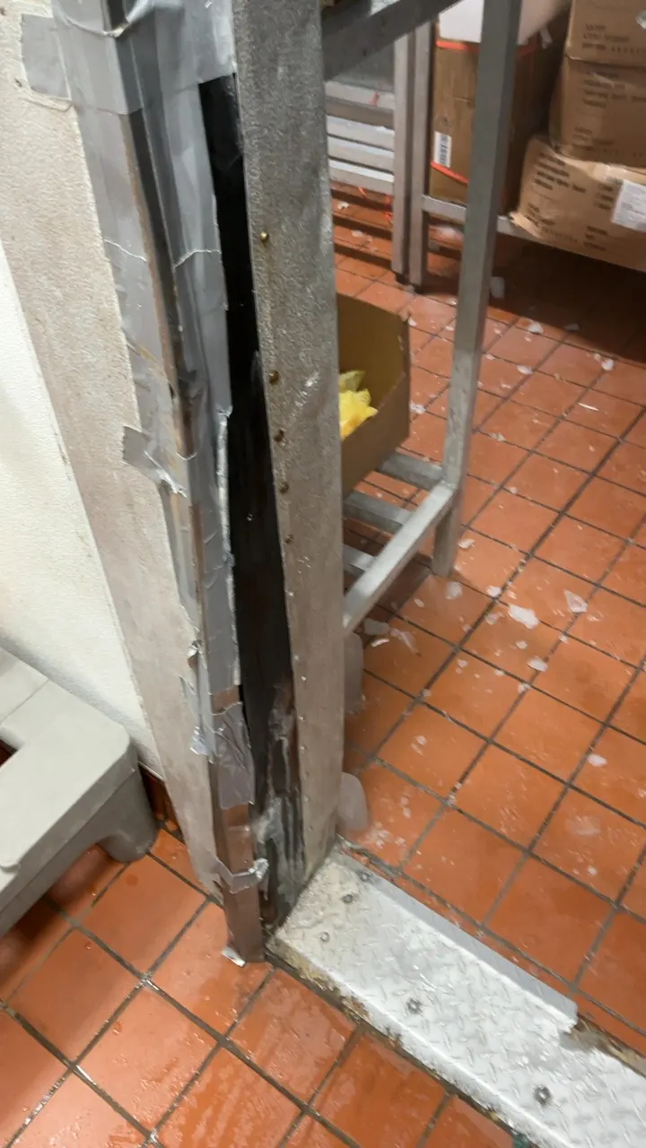 Walk-in cooler door jamb patched with duct tape as a temporary seal in a commercial kitchen